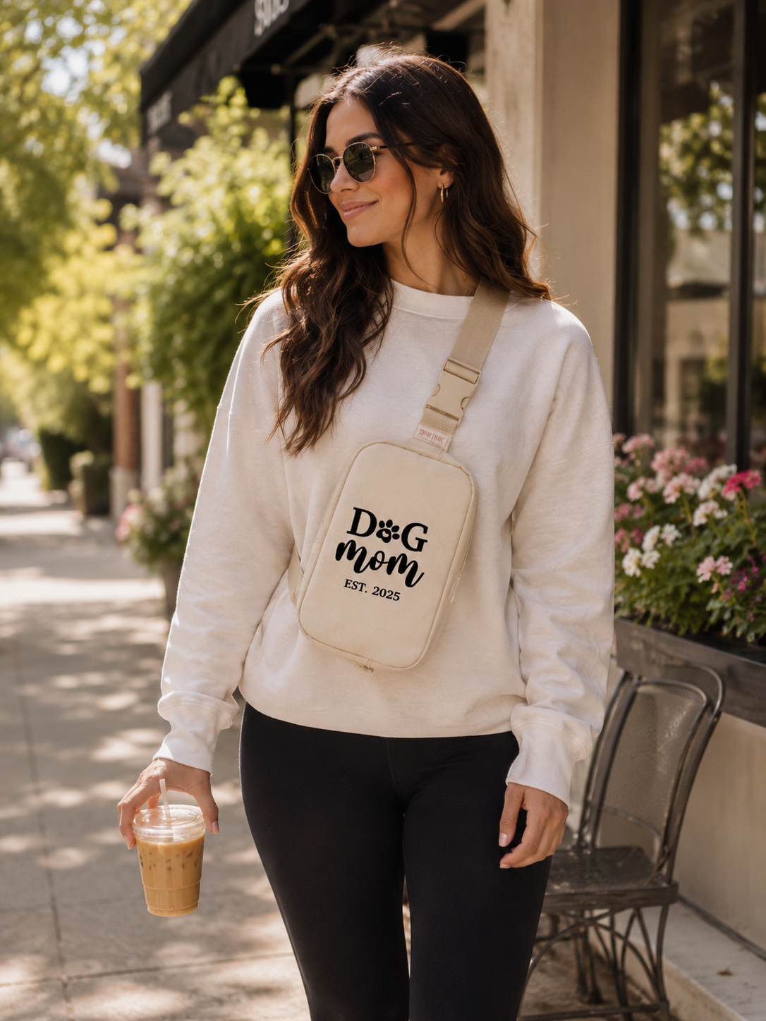 Woman walking outdoors with a 'Dog mom' crossbody bag and coffee cup