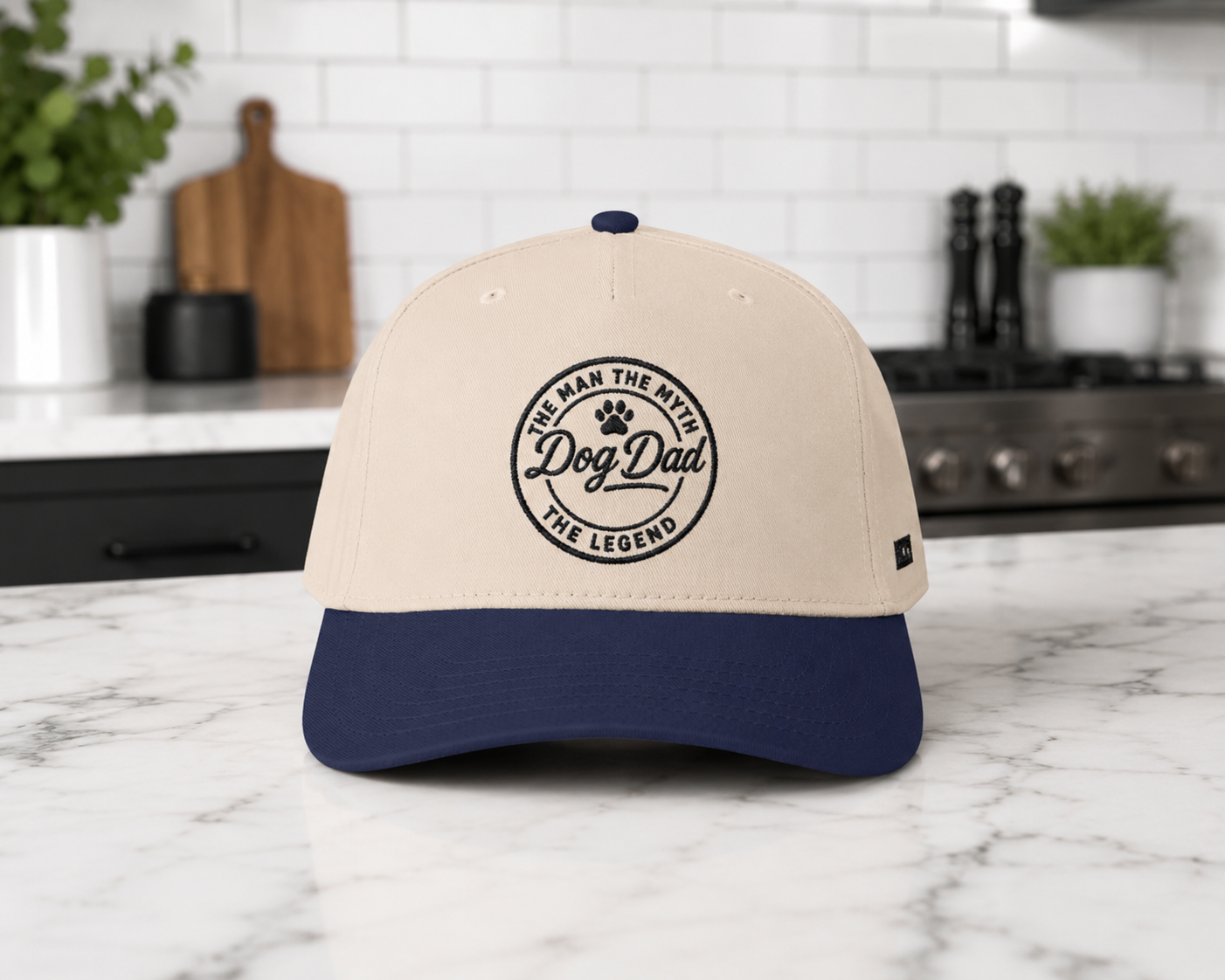 Beige and navy cap with 'Dog Dad' text on a marble kitchen counter