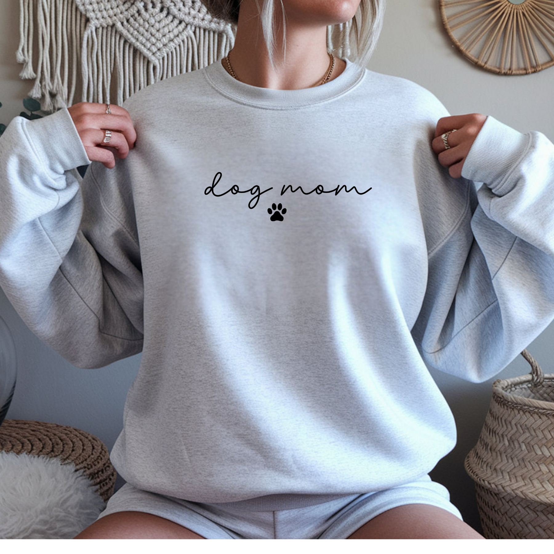 Person wearing a light gray sweatshirt with 'dog mom' text and paw print design.