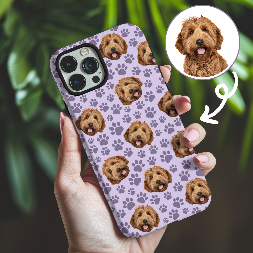 A phone case with a repeated pattern of a cute dog's face and paw prints in a purple color scheme, held in a person's hand.