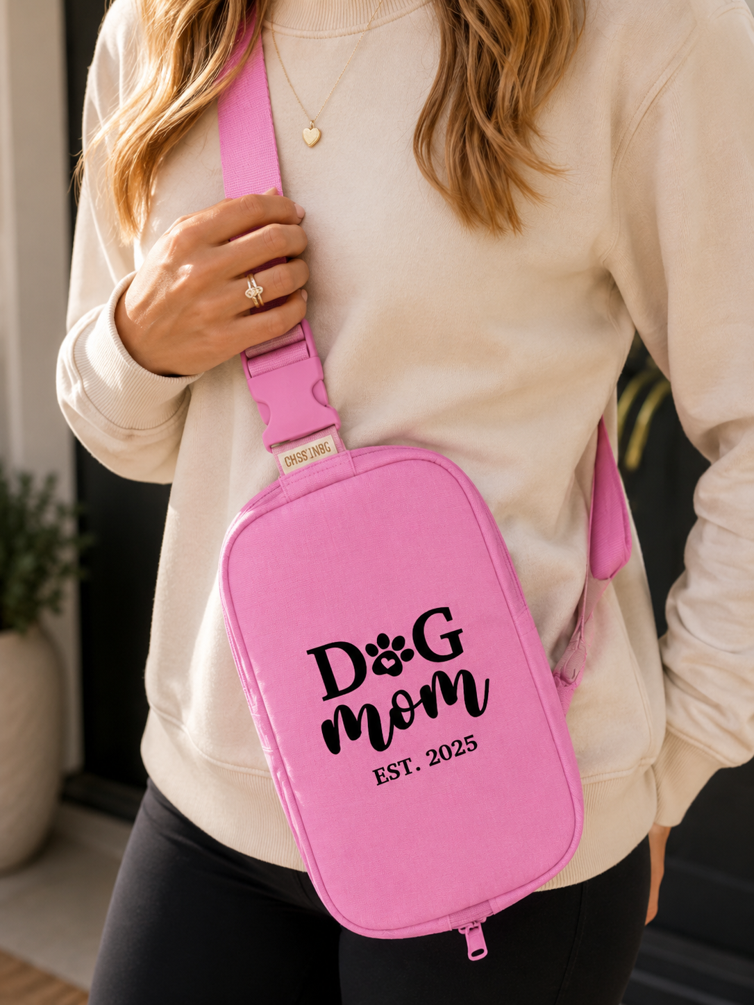 Person wearing a pink crossbody bag with 'Dog Mom Est. 2025' text.